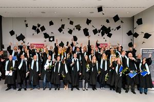 Glückliche Absolventen lassen ihre Hüte fliegen