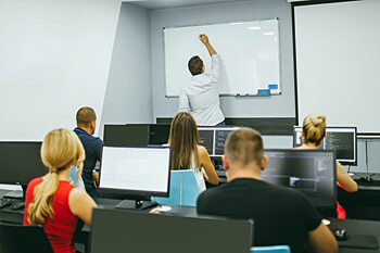 Studenten im Seminar vor PC´s und Dozent an der Tafel