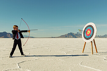 kleiner Junge mit Pfeil und Bogen in der Wüste