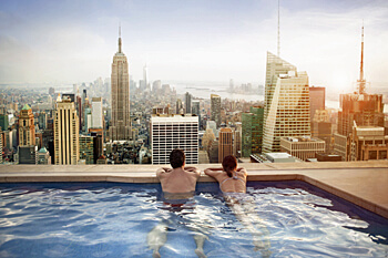 zwei Personen in einem Pool genießen die Aussicht auf die Skyline Manhattans